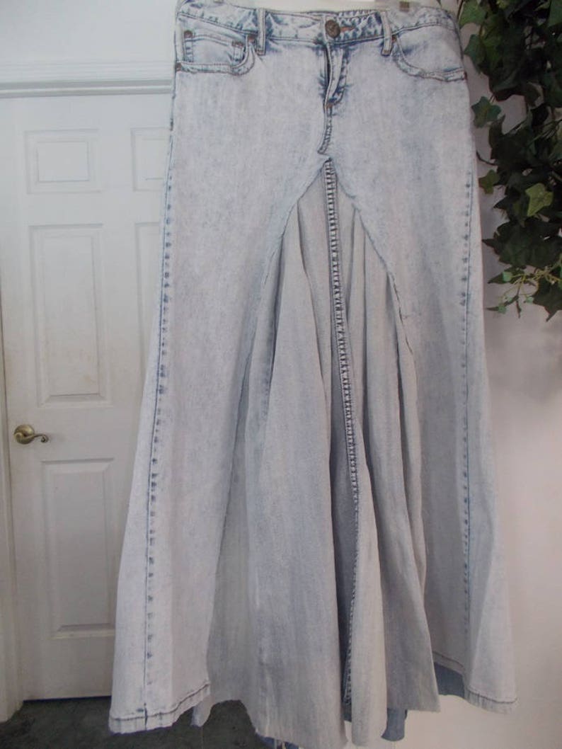 Puede incluir: Una falda maxi de mezclilla azul claro con una abertura frontal y un dise&ntilde;o plisado.