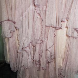 May include: A dusty rose tulle skirt with multiple layers of ruffles. The skirt is made of a soft, sheer fabric and has a flowing, romantic look.
