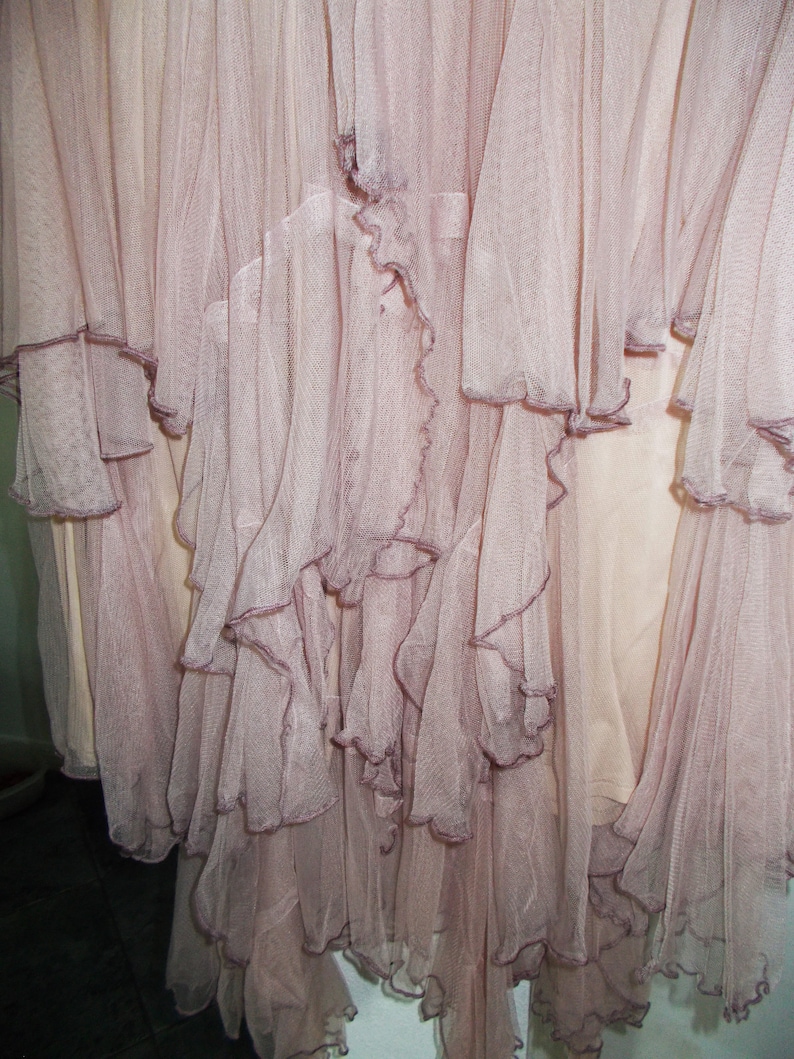 May include: A dusty rose tulle skirt with multiple layers of ruffles. The skirt is made of a soft, sheer fabric and has a flowing, romantic look.