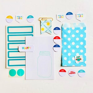 May include: A collection of stationery items, including stickers, labels, and a blue polka dot bag. The stickers have phrases like "make me smile" and "date." A paper with a jar outline and the word "Happy" is also included.