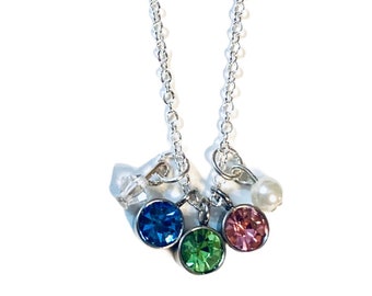 May include: A silver chain necklace with four charms: a blue crystal, a green crystal, a pink crystal, and a white pearl.