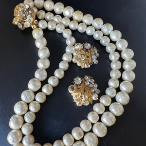 Peut inclure: Un collier de perles à double rang avec des accents dorés et en strass. Le collier est assorti à des boucles d'oreilles.