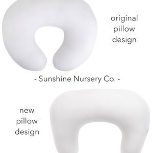 May include: Two white nursing pillows, one in the original design and one in a new design. The original design is a C-shape with a larger opening in the back. The new design is a C-shape with a smaller opening in the back. - Sunshine Nursery Co. -