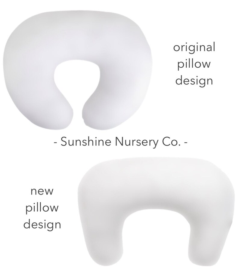May include: Two white nursing pillows, one in the original design and one in a new design. The original design is a C-shape with a larger opening in the back. The new design is a C-shape with a smaller opening in the back. - Sunshine Nursery Co. -