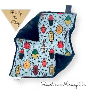 May include: A black and blue baby blanket with a pattern of colorful bugs and ants. The blanket is made of soft, plush fabric and is perfect for cuddling.
