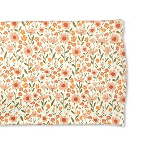 May include: A white fabric with a repeating pattern of pink and orange flowers. The flowers are stylized and have a vintage feel.