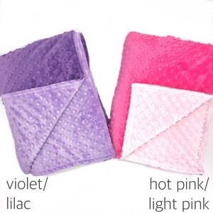 May include: Two folded blankets with a raised dimpled texture. The left blanket features a deep violet and a lighter lilac side. The right blanket features a vibrant hot pink and a soft light pink side. Text labels read violet/lilac and hot pink/light pink.