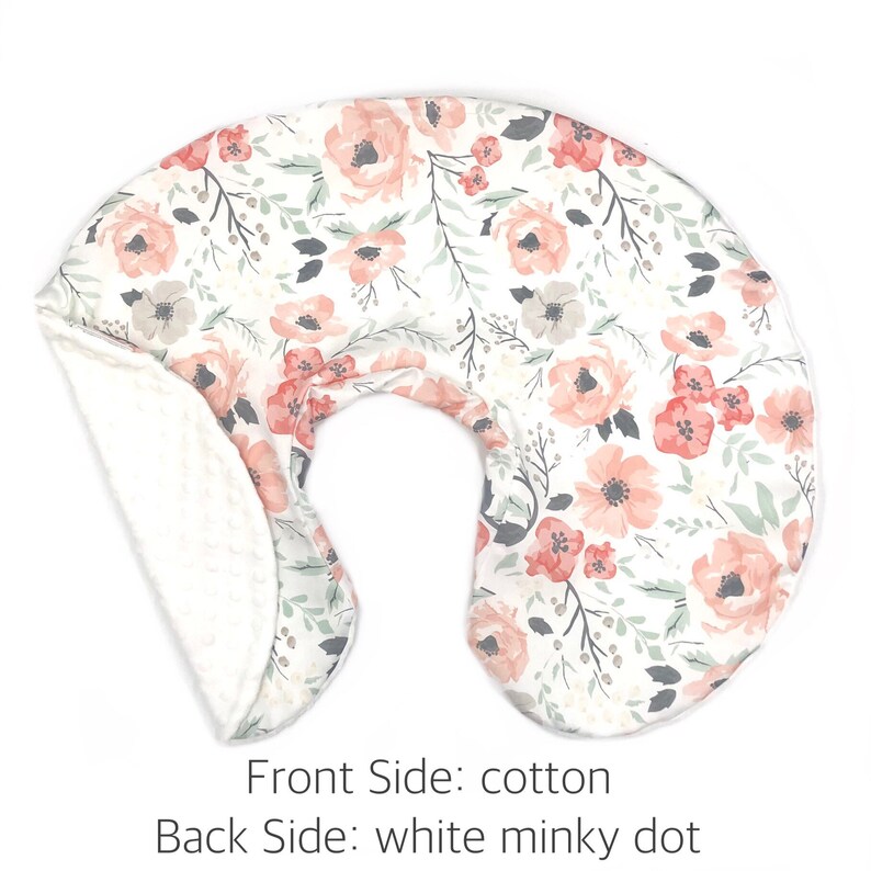 May include: A white and pink floral print nursing pillow with a white minky dot back.  Front Side: cotton. Back Side: white minky dot.