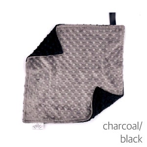 May include: A soft, gray and black baby blanket with a textured, dot pattern on one side. The blanket is made of minky fabric and is perfect for cuddling.