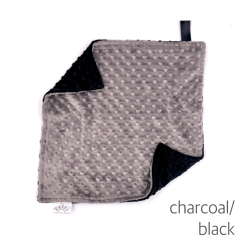 May include: A soft, gray and black baby blanket with a textured, dot pattern on one side. The blanket is made of minky fabric and is perfect for cuddling.