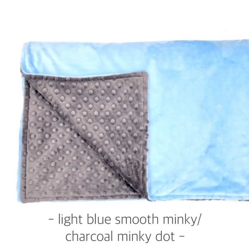 May include: A soft blanket featuring a smooth light blue minky fabric on one side and a charcoal gray minky dot fabric on the other. The text below the blanket reads: - light blue smooth minky/ charcoal minky dot -.