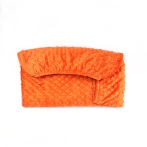 May include: A soft, orange, quilted baby blanket with a textured, dotted pattern.