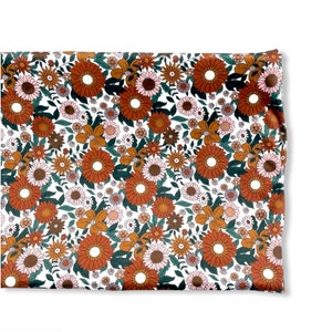 May include: White fabric with a repeating pattern of brown, orange, and pink flowers. The flowers are stylized and have a retro feel.