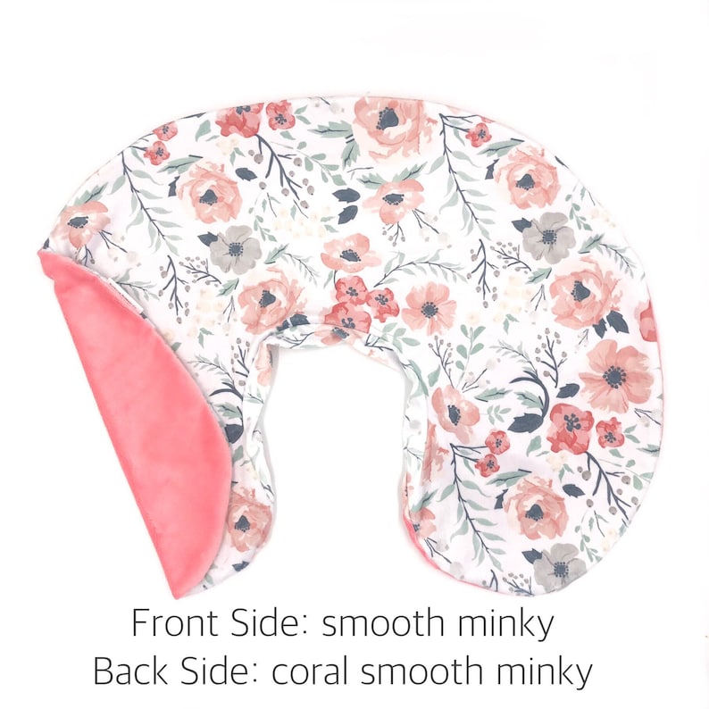 May include: A U-shaped nursing pillow with a floral print on the front and a solid coral minky fabric on the back.  The pillow is designed to provide support for mothers while breastfeeding or bottle feeding.
