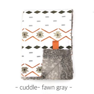 May include: A white and gray baby blanket with a geometric pattern in orange and green. The blanket is made of soft, cuddly fabric and has a faux fur backing.
