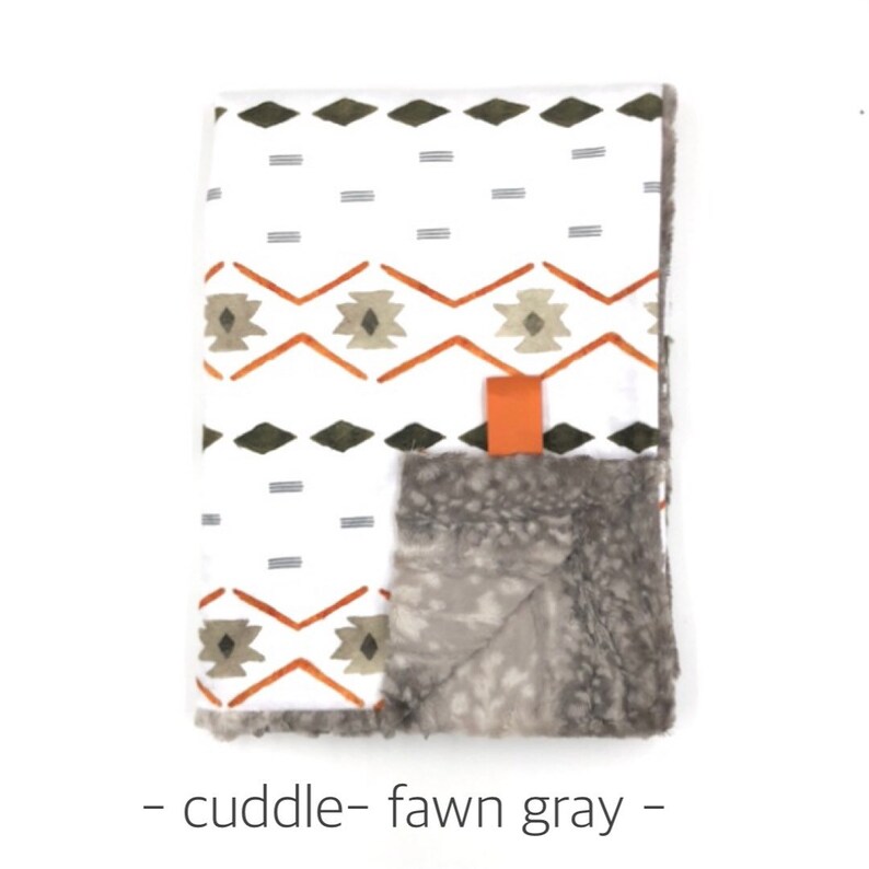 May include: A white and gray baby blanket with a geometric pattern in orange and green. The blanket is made of soft, cuddly fabric and has a faux fur backing.