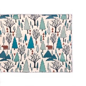 May include: A cream-colored fabric with a repeating pattern of blue and green trees, brown bears, and brown triangles. The pattern is on a white background.