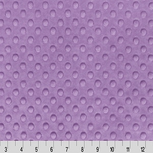 May include: A close-up of a lavender fabric with a raised dot pattern. The fabric has a soft, plush texture. A ruler is at the bottom of the image, with measurements in inches.