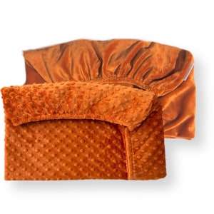 May include: Two orange fitted sheets, one with a textured surface and one with a smooth surface. The sheets are made of soft, plush fabric.