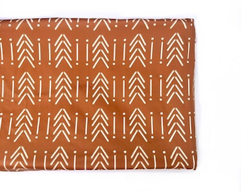 May include: A brown fabric with a white geometric pattern of arrows and dots. The fabric is folded in half.