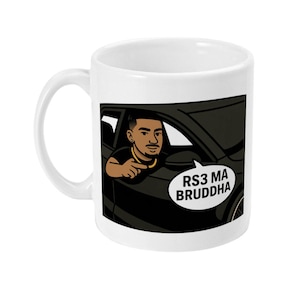 Puede incluir: Taza de cerámica blanca con una ilustración en blanco y negro de una persona conduciendo un coche. La persona está señalando al espectador y la burbuja de diálogo dice "RS3 MA BRUDDHA".