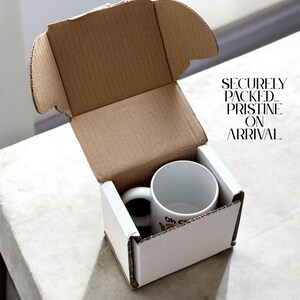 May include: A white ceramic mug with a black handle inside a white cardboard box. The mug has a cartoon design and the words "Oh C" printed on it. The box is inside a larger brown cardboard box. Text on the box reads "SECURELY PACKED. PRISTINE ON ARRIVAL."