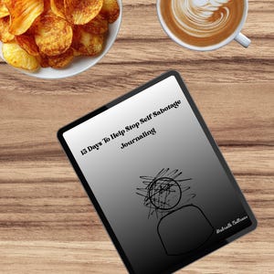 Op de afbeelding: Een houten tafel toont een witte kom met chips, een kopje koffie met zwanen-latte art en een dagboek. De kaft van het dagboek luidt "15 Days To Help Stop Self Sabotage Journaling."