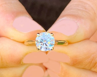May include: A gold engagement ring with a large, round, clear diamond.