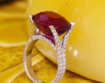 May include: A silver ring with a large, deep red gemstone surrounded by smaller white gemstones.