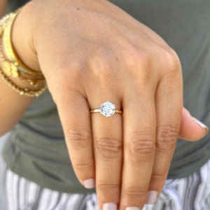 Op de afbeelding: Een close-up van een hand met een gouden ring met een grote, ronde, heldere diamant.