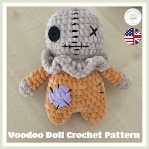 May include: A handmade crochet voodoo doll with a gray head, black button eye, and stitched mouth. The doll has an orange body with a purple patch and gray arms. The text "Voodoo Doll Crochet Pattern" is at the bottom.