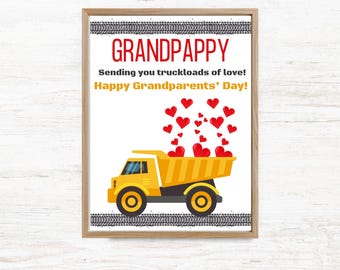 May include: A framed print featuring a yellow dump truck carrying red hearts. The text reads: GRANDPAPPY, Sending you truckloads of love!, Happy Grandparents' Day!. The design includes black tire tracks at the top and bottom of the white background.
