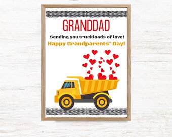 May include: A framed print featuring a yellow dump truck with a bed full of red hearts floating upward. The text reads GRANDDAD, Sending you truckloads of love!, and Happy Grandparents' Day! with black tire tracks at the top and bottom.