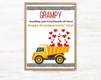 May include: A framed print featuring a yellow dump truck carrying red hearts, with tire tracks at the top and bottom. The text reads: GRAMPY, Sending you truckloads of love!, Happy Grandparents' Day! The design is set against a white background.