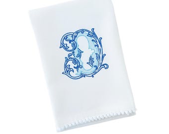May include: White cotton tea towel with a blue embroidered letter D with a decorative floral design. The towel has a white pom-pom trim.