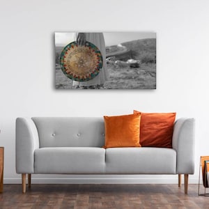 May include: A black and white photograph of a person holding a round, colorful, patterned disc. The disc has Hebrew writing on it. The person is standing in a field with a road in the background.