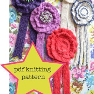 May include: Four knitted flower brooches with long, matching knitted ribbons. The flowers are in shades of purple, pink, red, and white. The brooches are displayed on a floral fabric background with a yellow star that says "pdf knitting pattern".