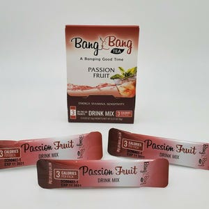 May include: Three individual packets of Bang Bang Tea Passion Fruit Drink Mix. Each packet is red and white with the Bang Bang logo and text that reads "Passion Fruit Drink Mix" and "3 Calories Per Pack".