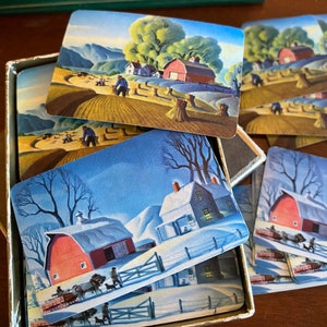 Op de afbeelding: Een vintage set speelkaarten met illustraties van boerderijscènes. De kaarten tonen een rode schuur, een boerderij en een veld met hooibalen. De kaarten zijn in goede staat en zouden een geweldige aanvulling zijn op elke kaartencollectie.