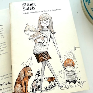May include: Vintage book cover titled "Sitting Safely: A Brief Safety Guide for Teen-Age Baby Sitters." The illustration depicts a woman holding a baby, a dog, and a child being watered by a watering can. The cover is off-white with black and brown illustrations.