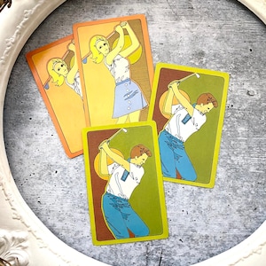 May include: Three illustrated cards featuring people playing golf. The cards are yellow, orange, and green with brown accents. The people are wearing blue and white clothing.