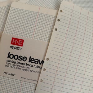 Pode incluir: Uma pilha de folhas soltas em tom esbranquiçado com pauta de livro de trânsito de mineração, apresentando um padrão de grade e seis furos. A embalagem exibe o logotipo K+E, o modelo 82 0279 e as dimensões 7 1/4 por 4 5/8 polegadas impressas.