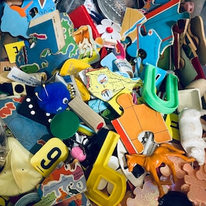 Puede incluir: Un surtido colorido de piezas de rompecabezas de madera, que incluye una pieza azul y verde con forma de herradura, una pieza amarilla con forma de letra 'U' y una pieza roja con el texto 'PACIFIC OCEAN'.