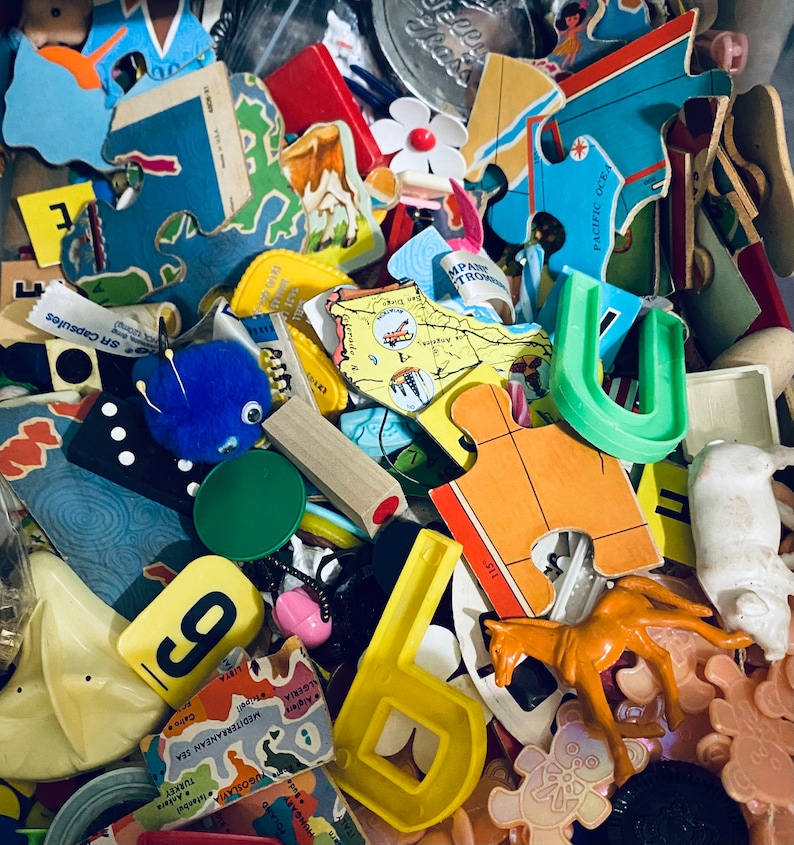 Op de afbeelding: Een kleurrijk assortiment houten puzzelstukken, waaronder een blauw en groen stuk in de vorm van een hoefijzer, een geel stuk in de vorm van een letter 'U' en een rood stuk met de tekst 'PACIFIC OCEAN'.