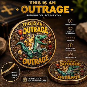 May include: A round collectible coin with an antique finish featuring a green dinosaur ridden by a cat wearing a crown. The text reads THIS IS AN OUTRAGE. The coin has a textured black background with small skulls and a trophy. It is 3mm thick.
