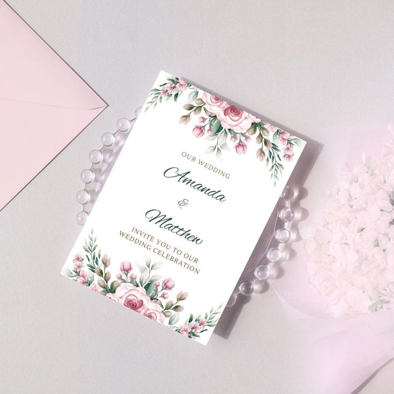 May include: A white wedding invitation with a floral design featuring pink roses and green leaves. The text reads "Our Wedding Amanda & Matthew Invite you to our Wedding Celebration."