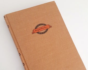 May include: A brown book with a black and orange sticker on the front cover. The sticker says "Signature Books" with a handwritten signature.