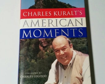 May include: A book titled "Charles Kuralt's American Moments" with a photo of Charles Kuralt on the cover. The book has a blue and red background with a foreword by Charles Osgood.