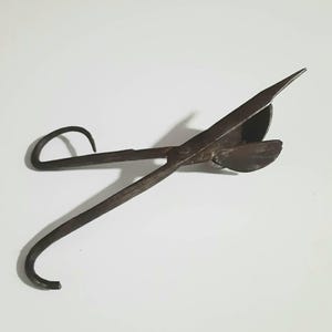 May include: A vintage metal tool with a long handle and a curved blade. The tool is designed for cutting and shaping materials.