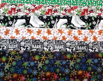 May include: A collection of six folded fabric strips featuring various holiday patterns including green with small snowmen, snowmen with scarves, white ice skates on black, gingerbread men, black with white text reading lets bake, and colorful snowflakes.